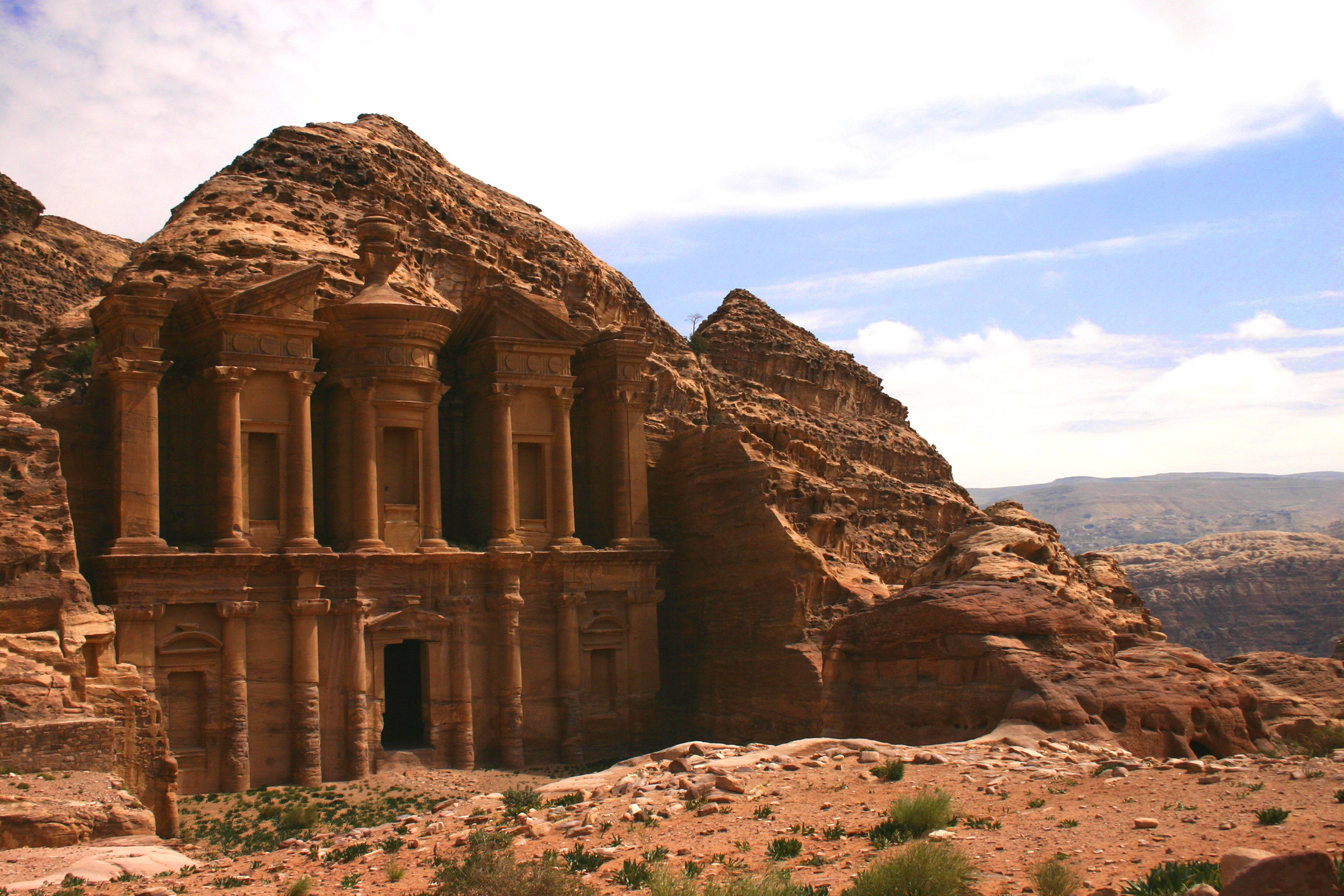Ancient carved stone monument facade set into a rocky mountainside under bright sky